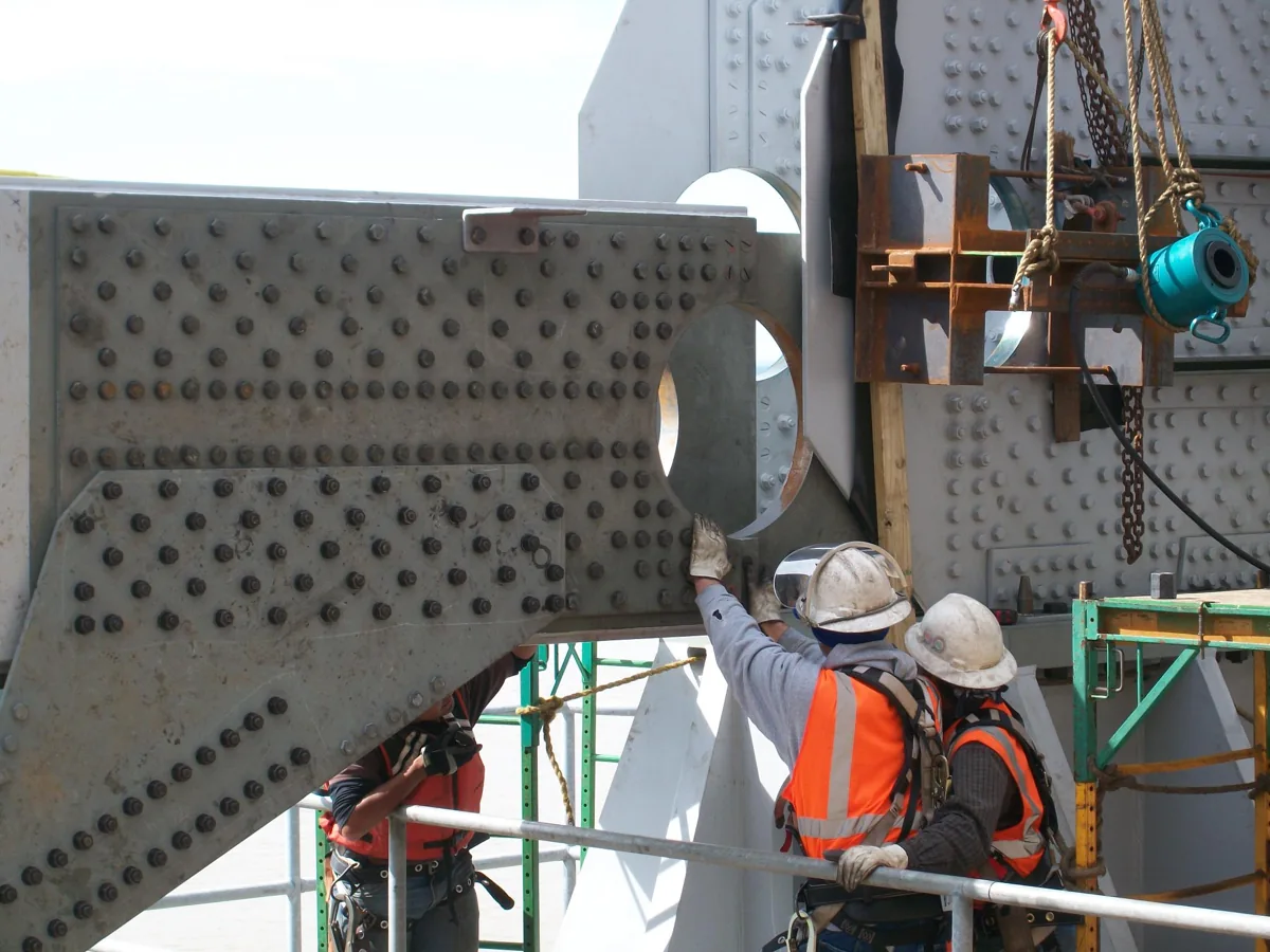Workers assembling a large bolted steel bridge connection